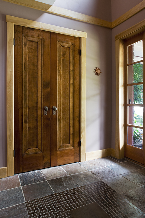 EXPANDED FRONT ENTRY CREATES ROOM FOR FOYER, RECLAIMED ANTIQUE DOORS FOR NEW COAT CLOSET. TILE CARPET.