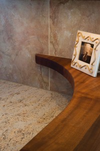 NARROW SAPELE MAHOGANY COUNTERTOP FINISHES WITH A CURVE TO THE WALL CREATING A PLACE FOR DISPLAY.