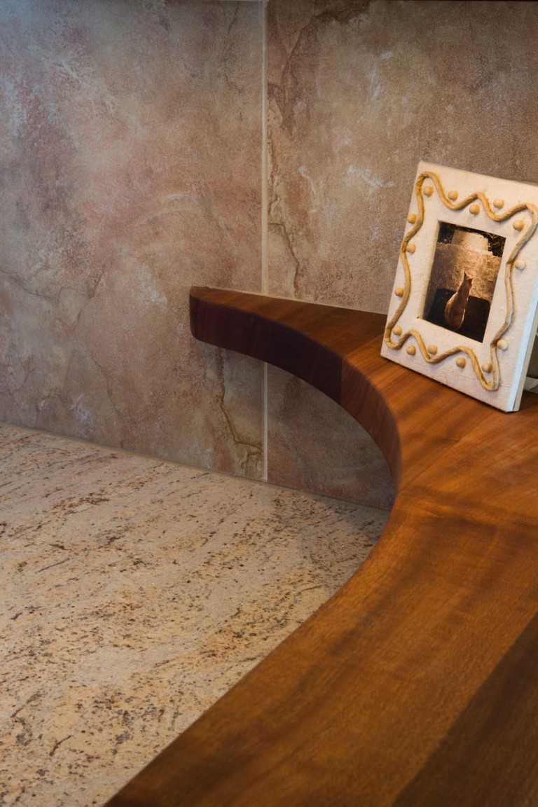 NARROW SAPELE MAHOGANY COUNTERTOP FINISHES WITH A CURVE TO THE WALL CREATING A PLACE FOR DISPLAY.